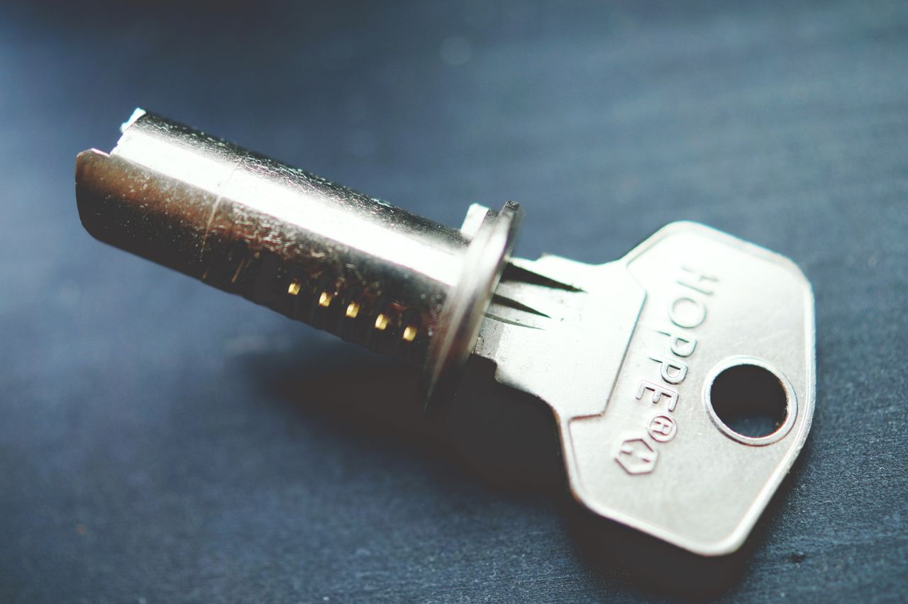 our-experience Detailed close-up image of a metallic key with lock cylinder on a dark surface, highlighting intricate details.