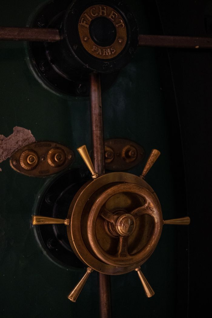 gallery-6 Close-up of a vintage safe door with a brass handle and dark green surface.