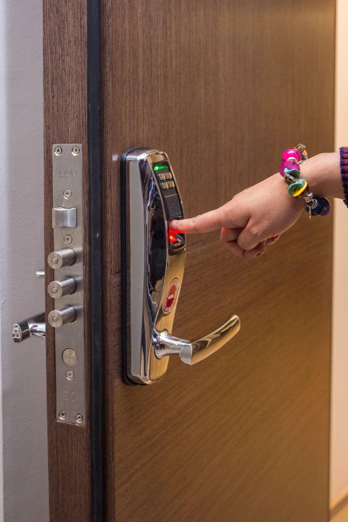 gallery-5 A hand using fingerprint access on a digital security door lock, enhancing safety.